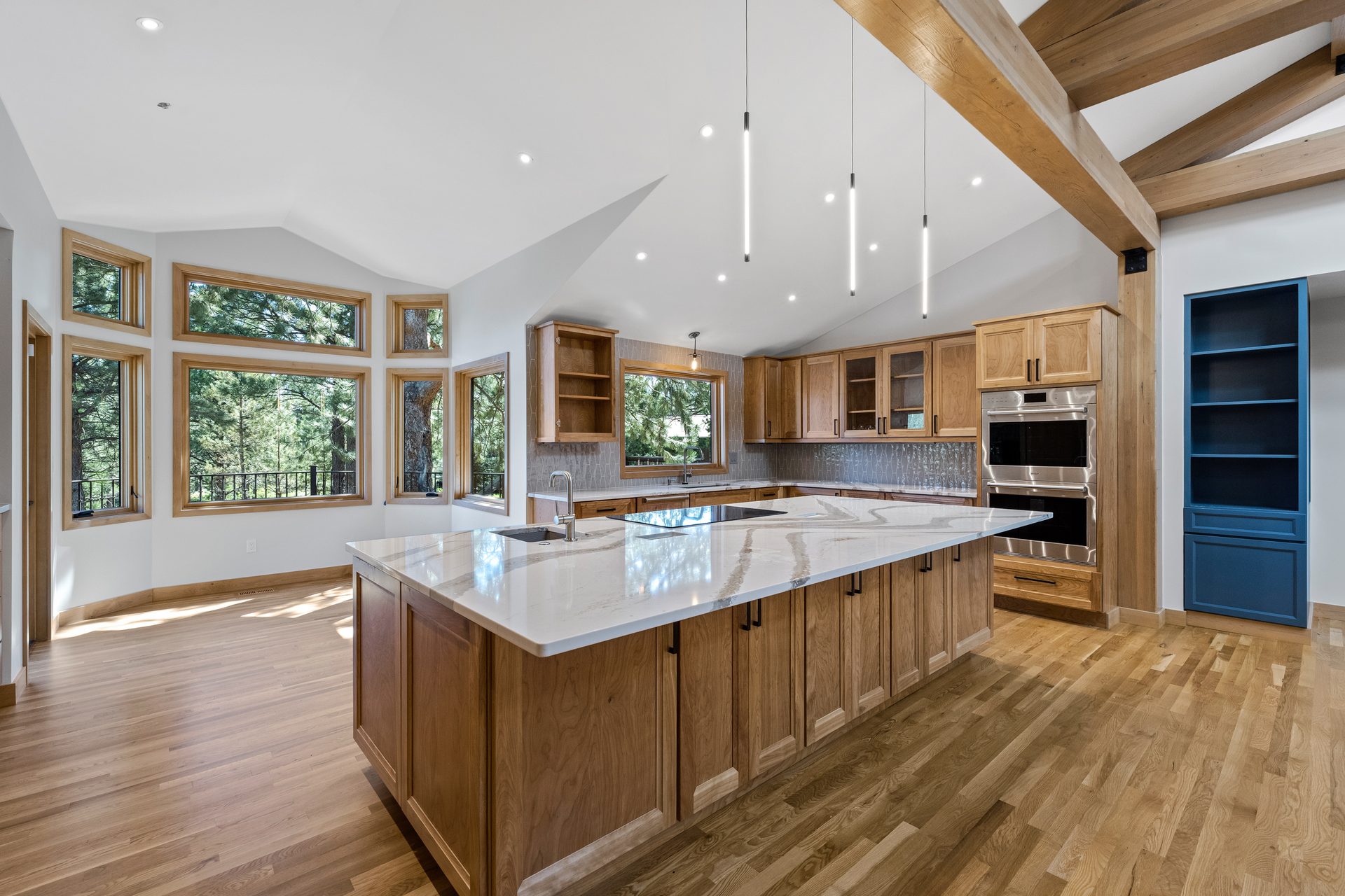 Custom kitchen with oversized quartz island, cherry cabinetry, and exposed timber trusses