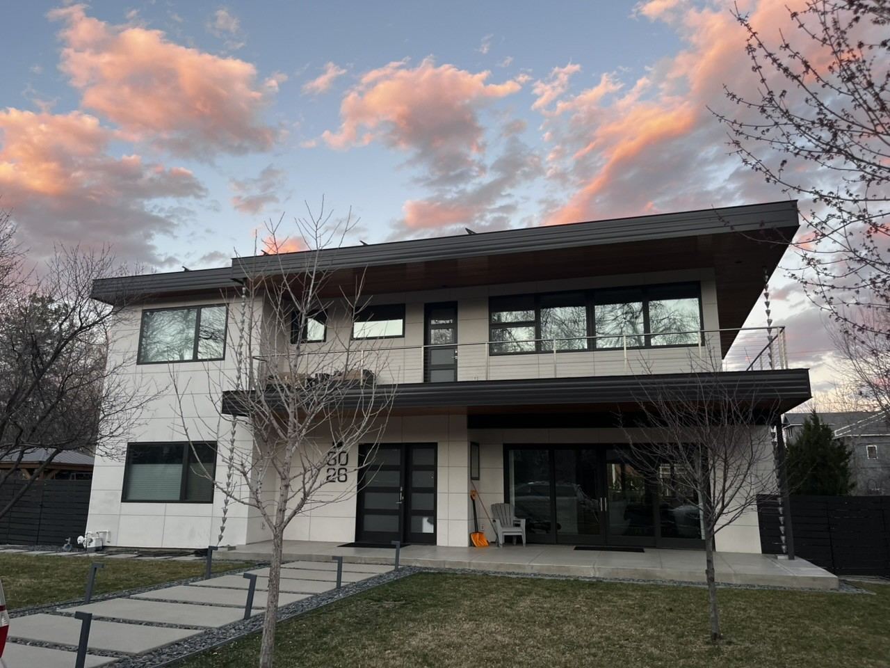 Modern two-story home remodel in Boulder, CO at dusk, with balcony and paver walkway